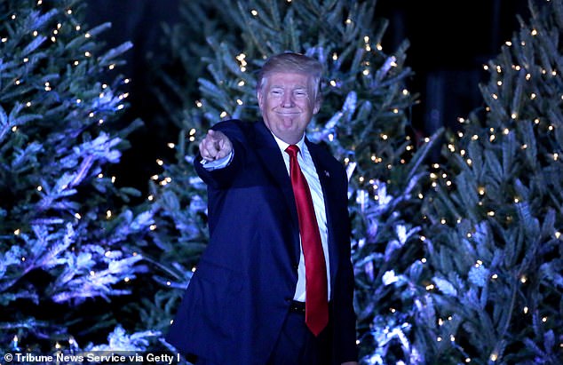 Former President Donald Trump, seen in 2016, offering Christmas wrapping paper with the mugshot taken as he was being processed in Fulton County, Georgia