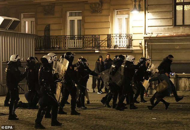 Pictured: Police officers take position as opposition supporters try to storm the Belgrade mayor's office