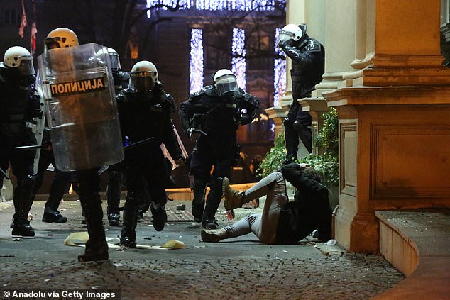 Police corner a protester on the ground outside city hall