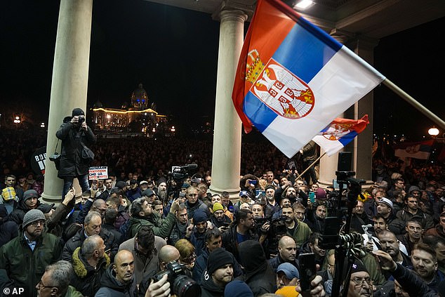 Protesters outside the Serbian capital's council building wave national flags during a demonstration against irregularities in last week's elections