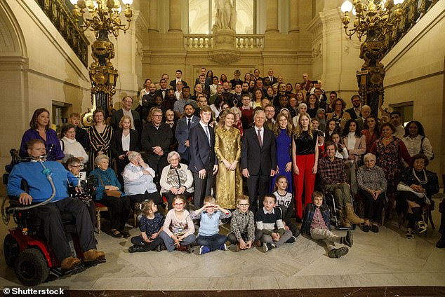 The royals took a group photo with the guests, and other sweet photos of the family show them standing by a decorative Christmas tree — and later among the red seasonal flowers