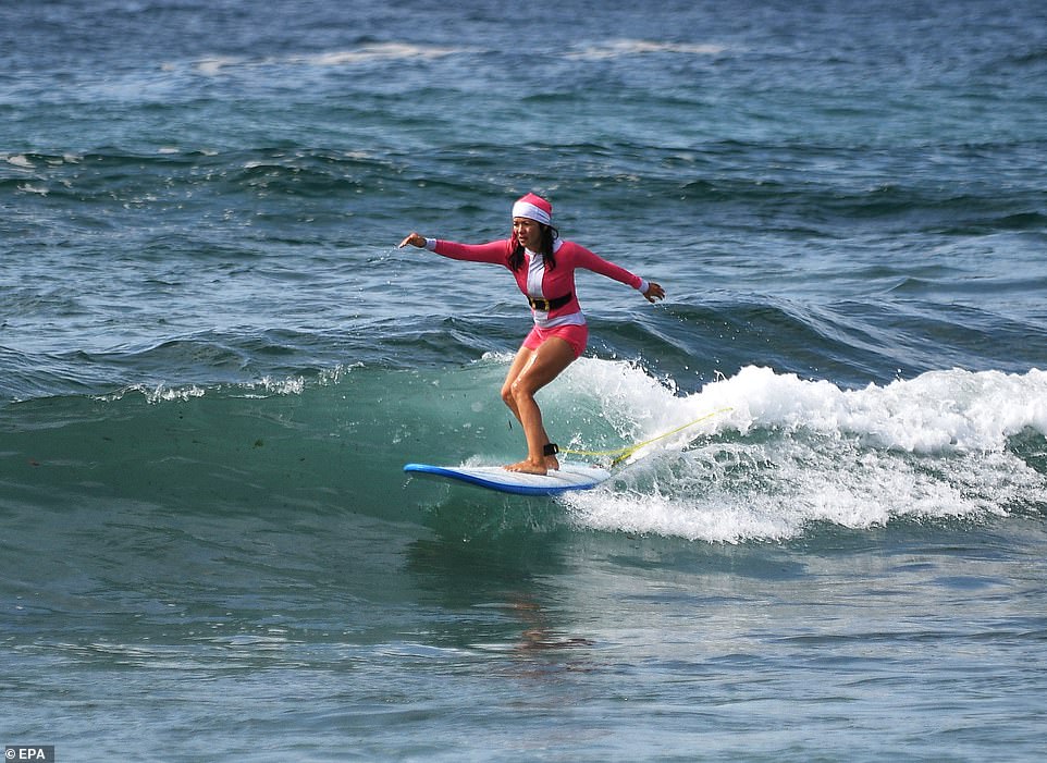 A woman donned a Santa suit and matching hat as she hit the waves on Christmas Day