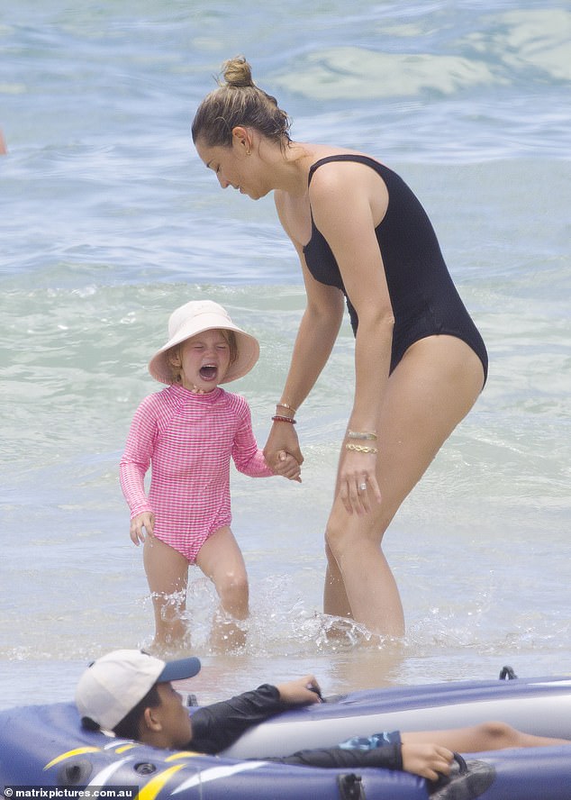 Jasmine comforted their three-year-old daughter Harper when she was shocked by the cool blue waters of the sea