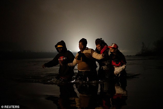 Migrants wade through the waters of the Rio Grande, the river that separates the US from Mexico near Eagle Pass, Texas