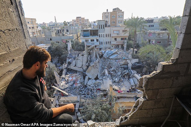 Pictured, Palestinians gather around the rubble of destroyed buildings after an Israeli bombardment in Deir El-Balah, central Gaza Strip, on Christmas Eve