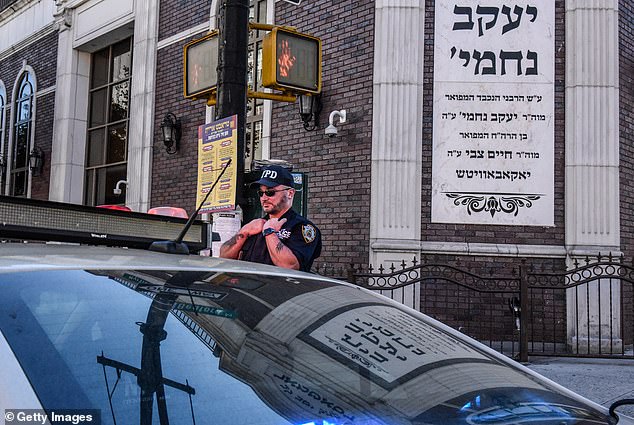 A member of the New York Police Department patrols outside the Bais Yaakov Nechamia Dsatmar synagogue congregation in Williamsburg, Brooklyn, on October 13.  The Secure Community Network, which monitors anti-Semitic threats and liaises with law enforcement, said the increase in beatings since Hamas's attack on Israel on October 7