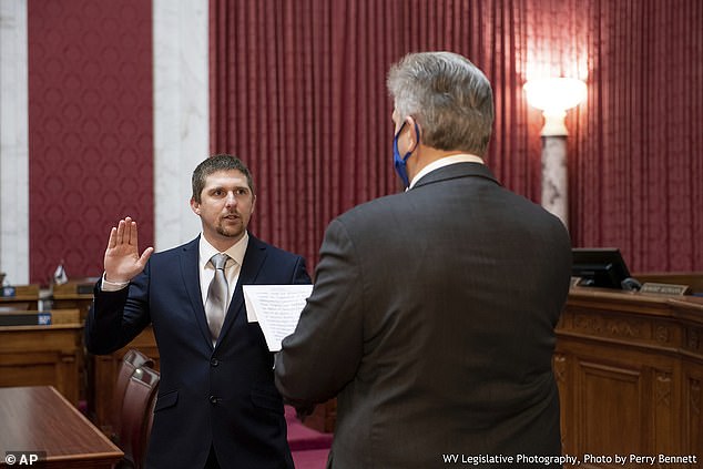 West Virginia House of Delegates member Derrick Evans (left) takes the oath of office on December 14, 2020 in the House chamber of the State Capitol in Charleston