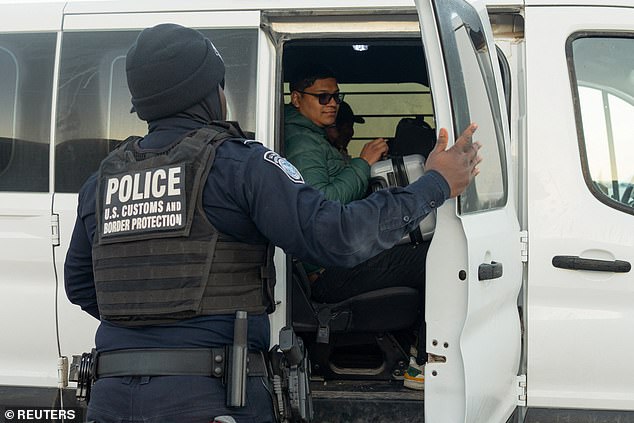 A U.S. Customs and Border Protection agent closes the door of a migrant transport van at the U.S.-Mexico border near Lukeville, Arizona, on Christmas Day