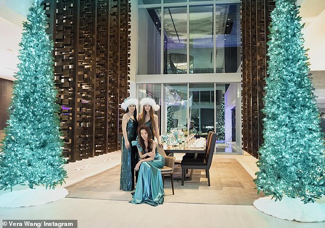 Cecilia and Josephine, the adopted children of designer and ex-husband Arthur Becker, stand side by side behind a seated Wang and also wear identical Santa hats