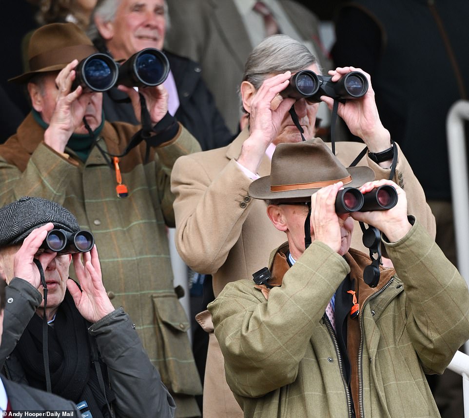 Keen punters use binoculars to get the best view of the horses in the distance on a popular day on the racing calendar