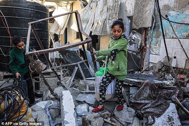 Palestinian girls search the rubble of a building after the Israeli bombing of Rafah in the southern Gaza Strip, on December 26, 2023