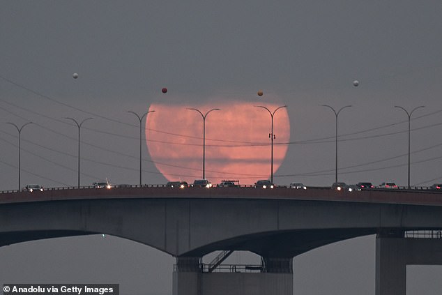 A cold full moon rises over the San Mateo Bridge and San Francisco Bay in San Mateo, California, US on December 26, 2023.