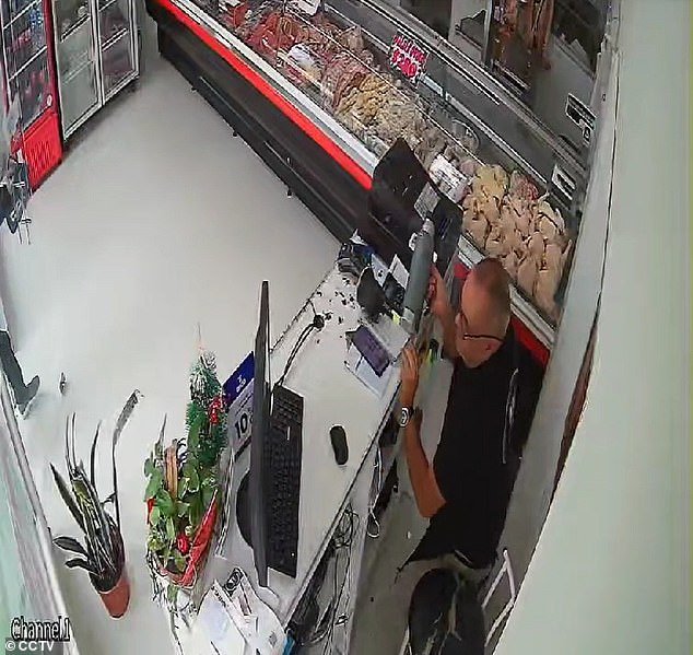 Business owner stands behind the cash register after he was able to stop a gunman from robbing his butcher shop, even though he was shot in the left arm