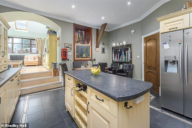 The kitchen has a central island and leads up some steps to an adjacent conservatory