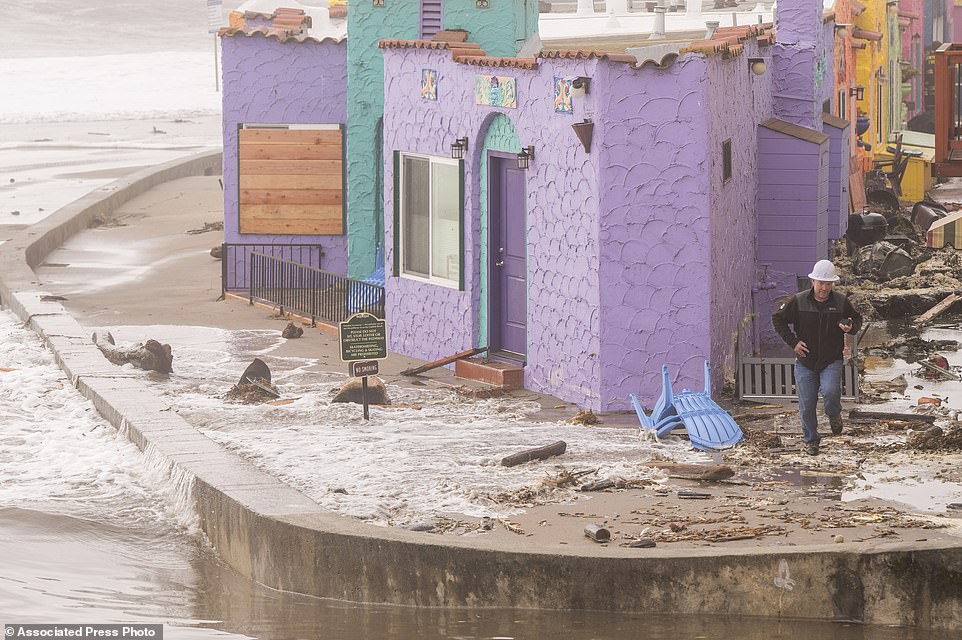 A utility worker runs from incoming water while inspecting broken power lines at The Venetian motel in Capitola