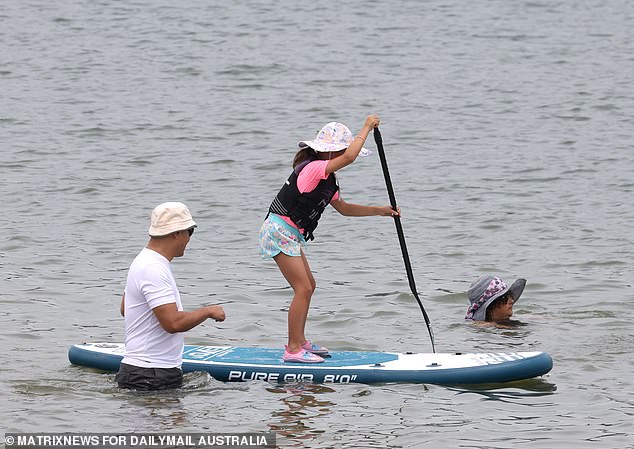 A man was seen teaching his daughter how to paddle board on the calm waters