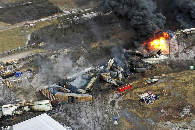 The debris from a Norfolk Southern freight train lies scattered and burning along the tracks