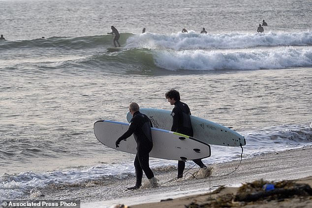 Surfers head out early Friday morning to catch the waves at Malibu Beach