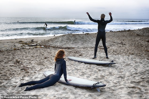 Surfers stretch before surfing Friday in Malibu Beach