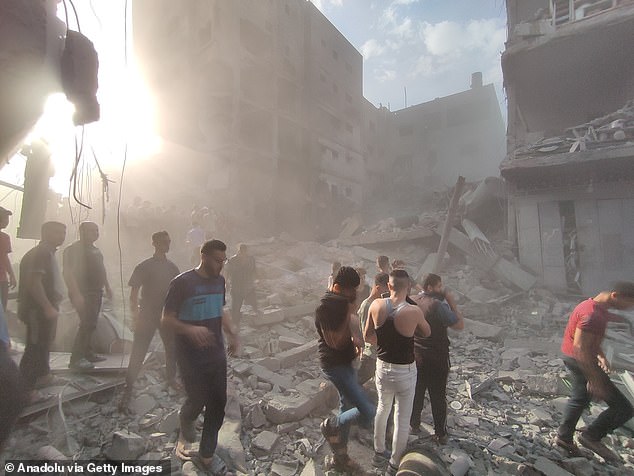Residents and civil protection teams conduct a search and rescue operation around the rubble of buildings following an Israeli attack on a building in Beit Lahia, Gaza