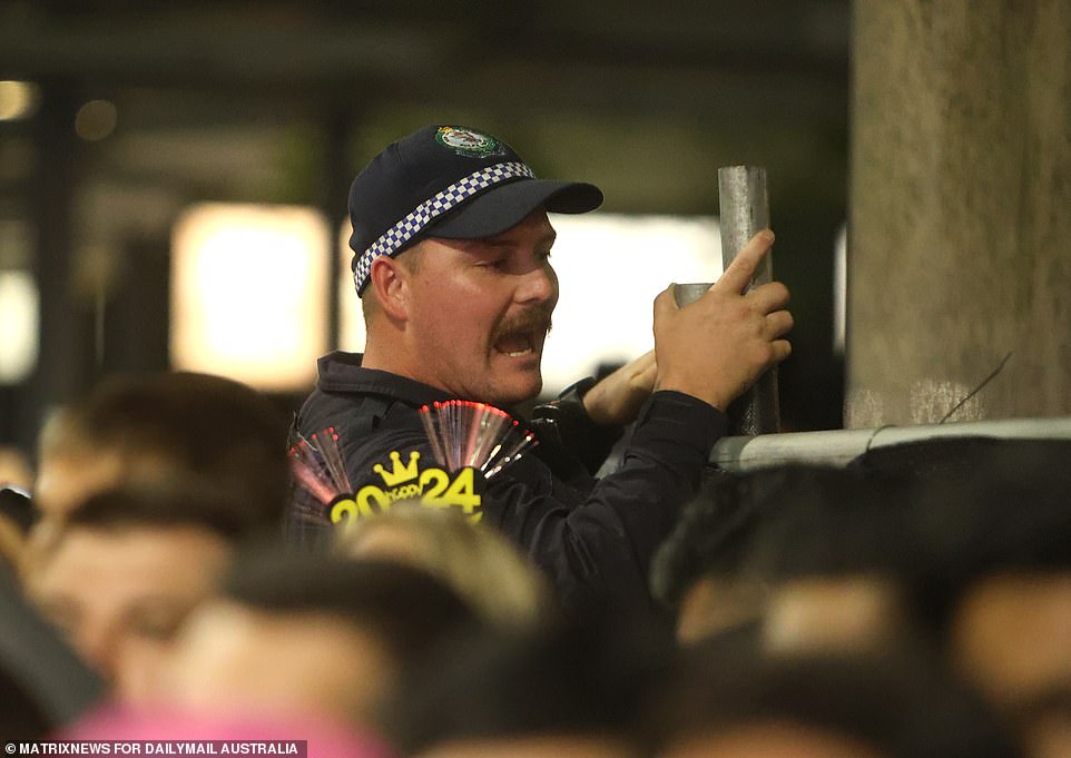 A police officer is seen leaning over a barrier, watching the action