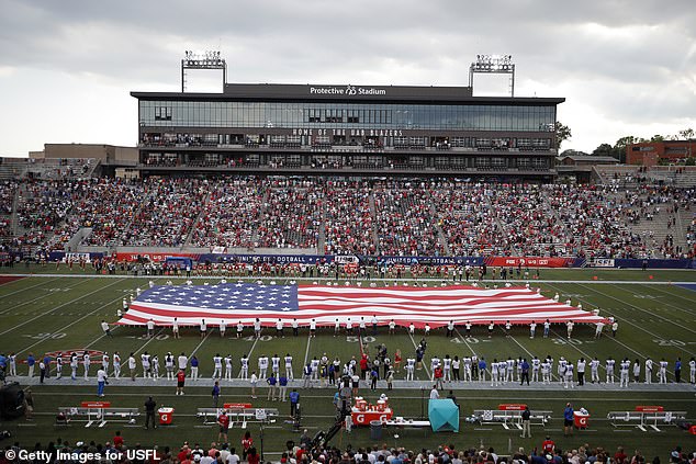 A giant flag is stretched over the field during the national anthem before a USFL game