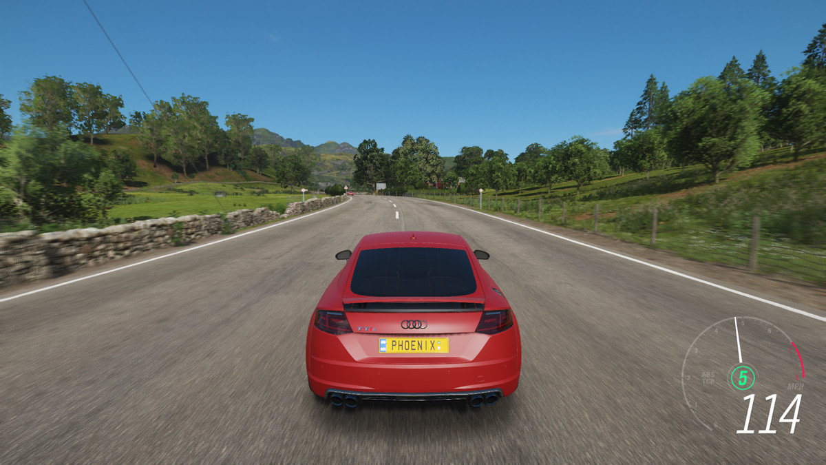 A red car races along a paved road in Forza Horizon 4