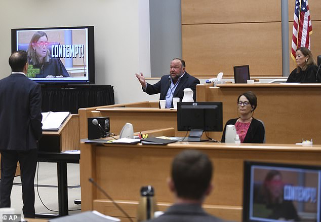 Conspiracy theorist Alex Jones is shown a photo of Judge Barbara Bellis with laser beams coming out of her eyes from his website during his testimony as Judge Bellis listens next to him, right, during the Sandy Hook defamation trial in September 2022. Jones is now trying to reduce the amount of compensation he had to pay