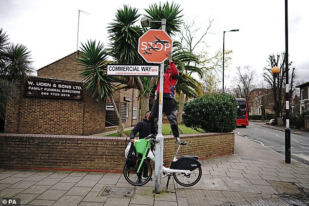 Two men were seen taking down the sign with pliers, with one balancing on an e-bike to reach it.