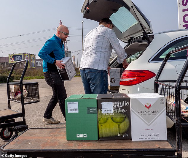 Customers pack their cars with wine boxes in the parking lot of the Calais Wine Superstore on April 7, 2019 in Calais, France