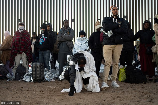 A migrant bows while awaiting Border Patrol transport at the U.S.-Mexico border near Lukeville, Arizona during Christmas