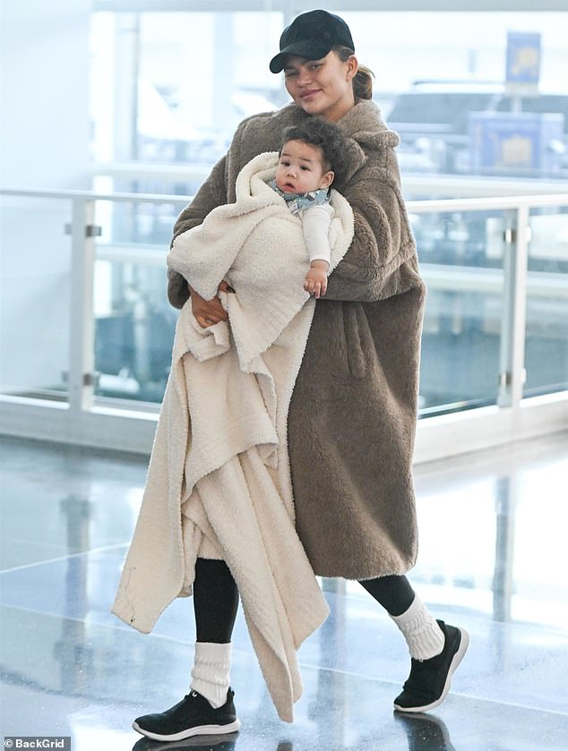 Chrissy Teigen, 38, looked relaxed as she walked through JFK airport on Saturday, wrapped in a fleece jacket while carrying six-month-old baby Wren