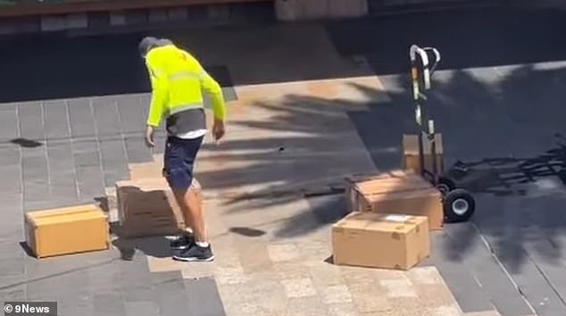 The worker was seen stacking six boxes that were scattered on the ground