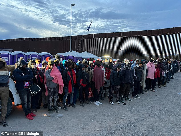 Immigrants line up for processing after crossing the US-Mexico border at Lukeville, Arizona