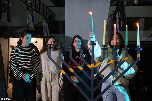 Released hostages Agam (2nd from left) and her mother Chen Goldstein (L) join members of Kibbutz Kfar Aza lighting the fourth Hanukkah candle as they call for the release of hostages