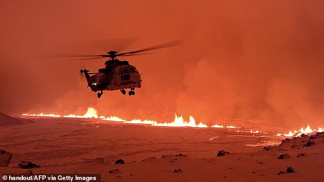 Emergency workers and scientists observe the billowing smoke and flowing lava that turns the sky orange.  This handout card from the Icelandic Coast Guard shows them flying over a volcanic eruption on the Reykjanes Peninsula, 3 km north of Grindavik, on Monday evening.