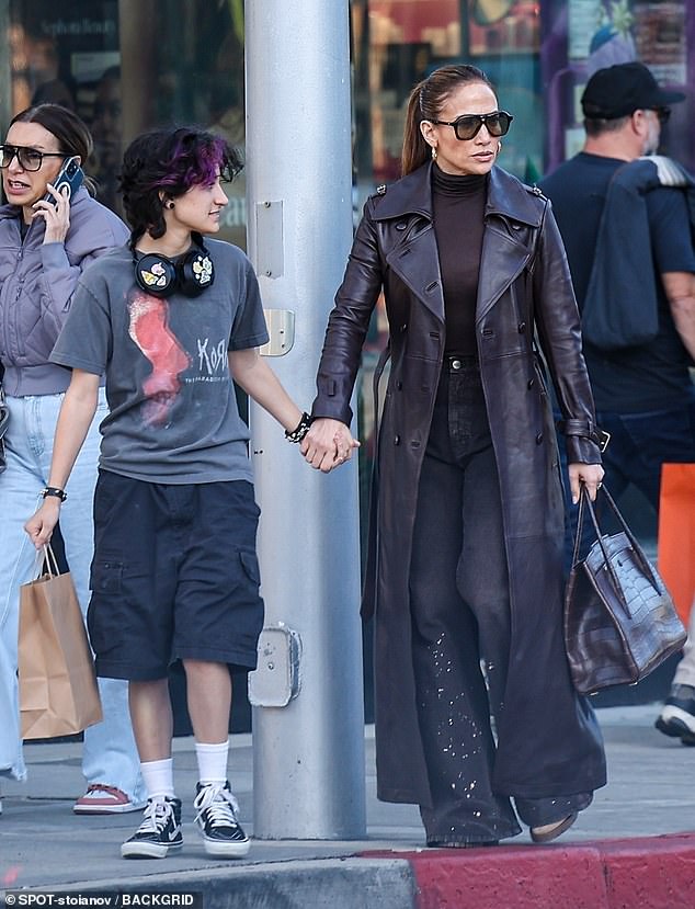 Jennifer Lopez was stylish in a dark leather trench coat and fitted turtleneck as she stepped out with one of her two twin children, Emme, in Los Angeles on Saturday