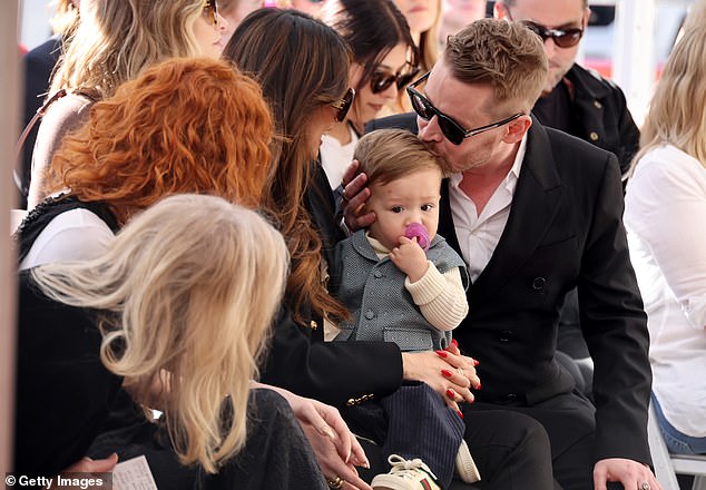 Macaulay Culkin was honored with a star on the Hollywood Walk of Fame in Los Angeles on Friday, December 1.  He was accompanied by both his sons.  In the photo, a kiss is planted on the head of youngest son Carson during the ceremony