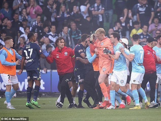 Glover is escorted off the ground after being attacked during the pitch invasion at AAMI Park in December last year