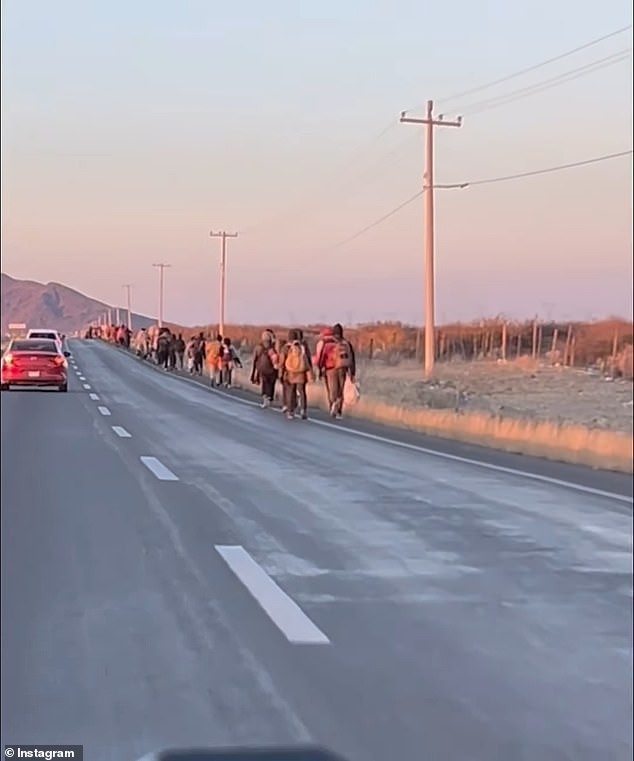 Migrants are seen walking towards the US-Mexico border south of Ciudad Juarez on Friday