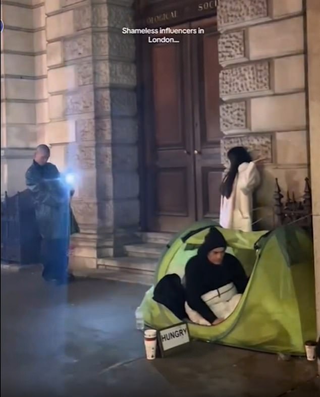 The woman posed for the camera against a wall, right next to a man in a tent