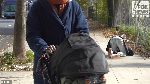 Francesca Barreiro pulls down the hood of her child's stroller so she doesn't see a man slumped on the sidewalk