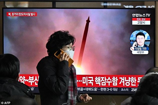 After North Korea fires another long-range missile, a woman in Seoul walks past a television screen showing a news broadcast showing file footage of an earlier missile test