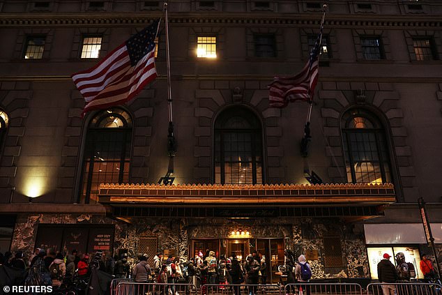 People stand outside the Roosevelt Hotel, which has served as a makeshift shelter for arriving migrants since May, in the Midtown section of New York City