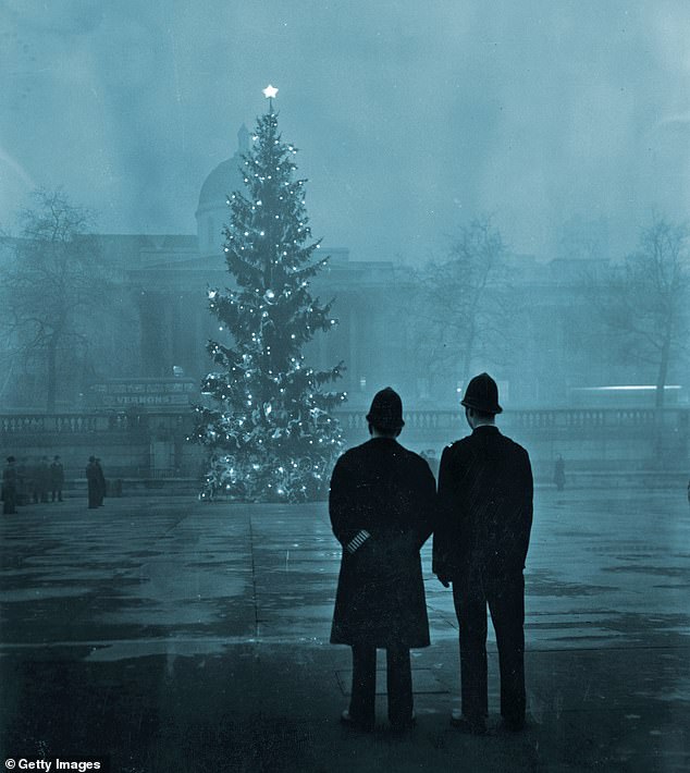 December 1, 1948: Two police officers view the 20 meter high London Christmas tree, a gift from Norway, illuminated in Trafalgar Square, in front of the National Gallery