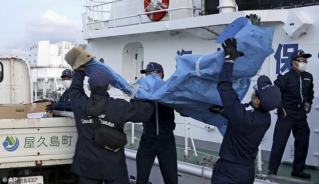 Members of the Japanese Coast Guard carry debris believed to be from the crashed US military Osprey aircraft