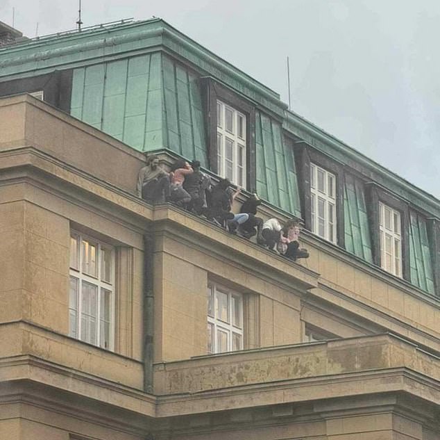 This extraordinary photo shows terrified students cowering on a ledge high on a faculty in an attempt to hide from the gunman