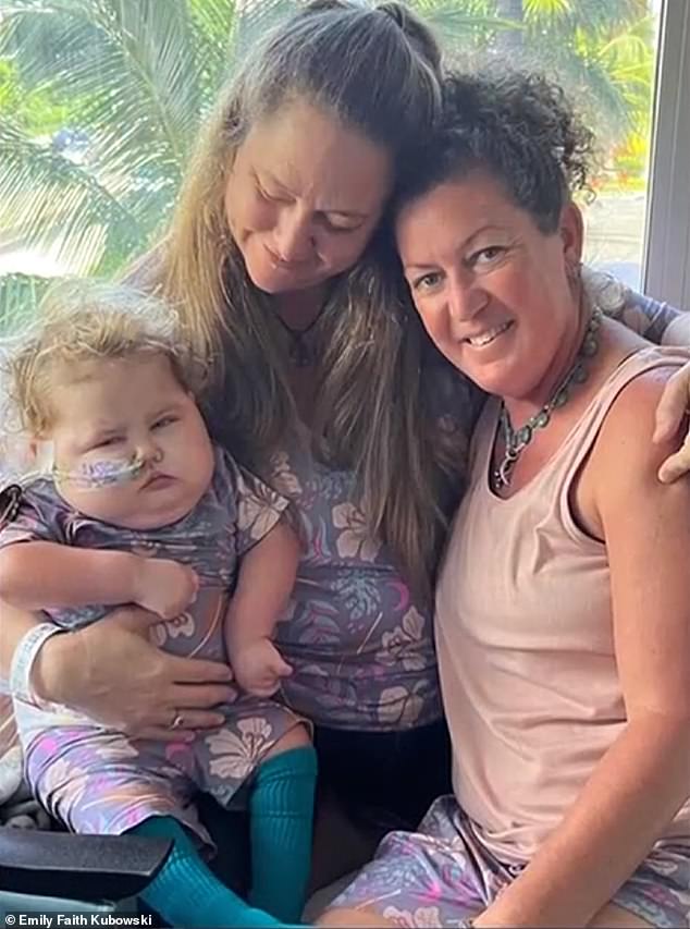 Emily Faith Kubowski's daughter Elowen almost died from rat lungworm disease.  The mother, seen above center with her partner, speaks out to raise awareness