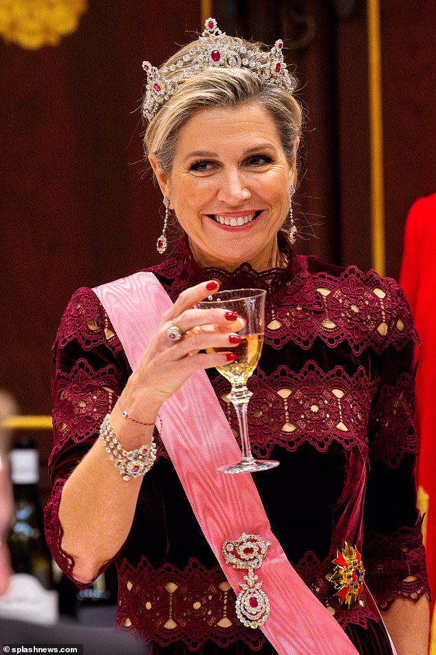 Queen Máxima of the Netherlands looked radiant in a burgundy dress with lace inserts as she attended a state banquet in Amsterdam this evening