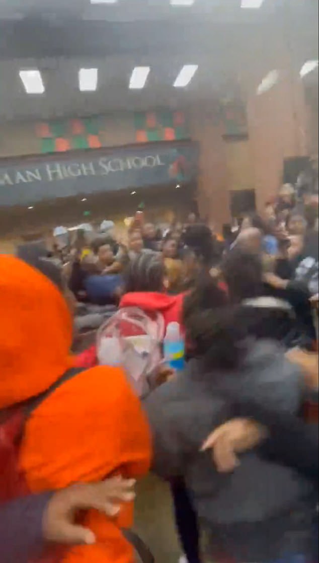 Two female students look at each other from the school lunchroom before one of them walks towards the other, while other students can be heard in the background.  One of the students then grabs the other by the top of her hair and tries to drag her past, while a person behind the camera shouts expletives